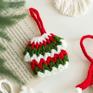 Handmade knitted Christmas sweater ornament in red white and green on a vintage book