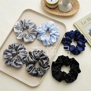 Detail view of a 6-piece satin scrunchie set in elegant neutral tones on a beige tray