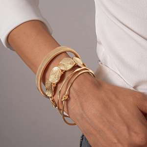 Detail of stacked gold geometric bracelets showing snake skin and hammered metal textures