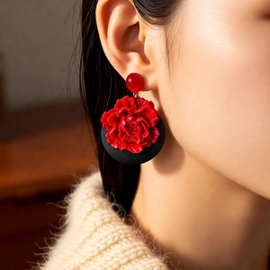 Close-up of a model wearing red flower earrings with vintage wood accents and black backings
