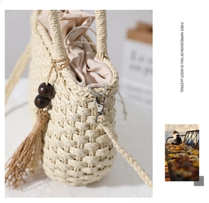 Detail of woven straw bucket bag showing wood bead tassel and drawstring inner pouch
