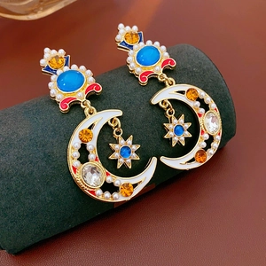Macro view of vintage gold moon earrings with blue crystals and white pearls