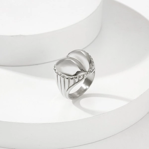 Macro shot of silver heart ring with vertical groove texture on a white geometric base