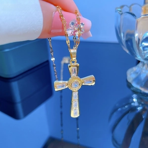 Close-up of gold titanium cross pendant with micro-pave crystals on a thin chain