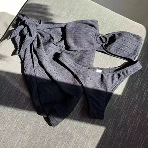 Detailed texture of black three-piece pointelle knit bikini and matching beach sarong