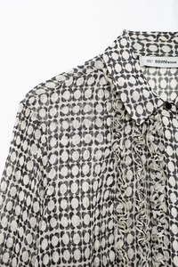 Detail of French style chiffon shirt featuring black and white abstract print and ruffles