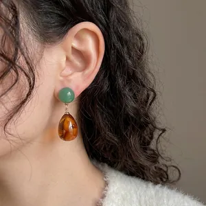 Vintage green and amber resin teardrop earrings with gold accents on model