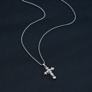Silver stainless steel cross necklace with stones on a blue textured background