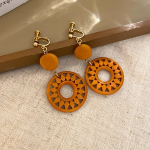 Macro shot of orange retro sunburst hollow resin earring with golden screw clip-on back