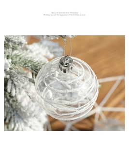 Close-up of a clear 6cm Christmas ball with white spiral glitter on a snowy tree branch