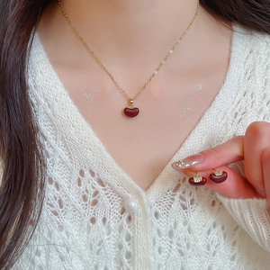 Detail of gold-plated apple earrings and necklace set with polished brown zircons