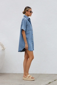 Profile view of a blue denim short sleeve shirt dress with collar and chest pocket details