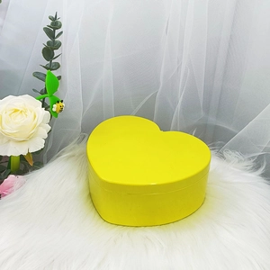 Detalle de joyero amarillo en forma de corazón sobre piel blanca con flores decorativas