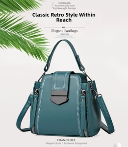 Detail view of a dark green leather handbag featuring a geometric black metal lock clasp