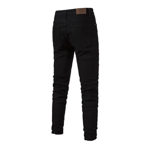 Detail view of the back pocket and leather brand patch on slim-fit black denim jeans