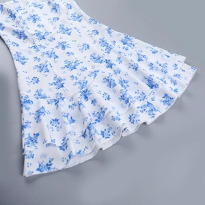 Dettaglio della stampa floreale blu sull'orlo a balze di un abito in chiffon