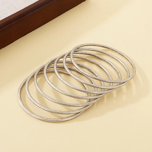 Detail view of 7-piece set silver stacked minimalist stainless steel wire coil bangles