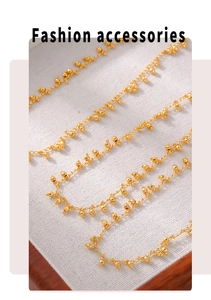 Macro view of gold plated bead tassel necklace on white textured jewelry cushion