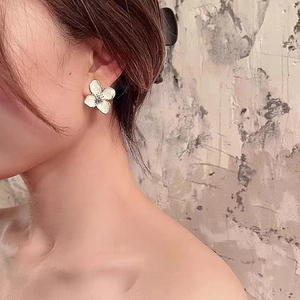 Vintage style white enamel flower earrings with pearl luster and metallic edges worn by model