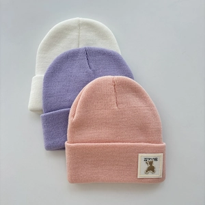 Detailed knit texture and embroidered bear patch on colorful winter beanies