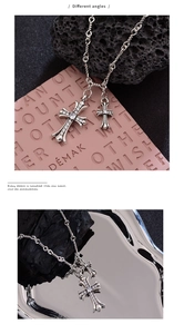 Macro detail of silver cross pendant necklace with zircon inlays on textured metal plate