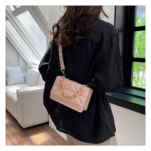 Detail of pink quilted crossbody bag with stylish patterned wide strap and chain accent