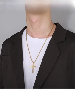 Polished gold stainless steel cross pendant necklace worn by a male model