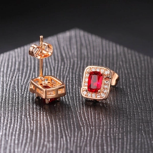 Macro view of rose gold stud earrings featuring red square zircon and white crystal halo