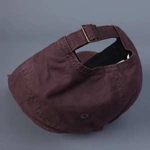 Detail of adjustable brass metal buckle on washed cotton baseball cap with neat stitching