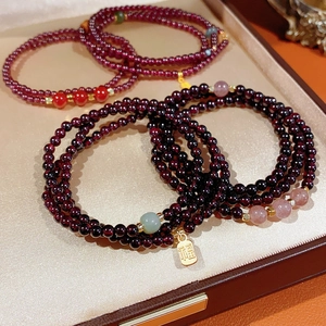 Macro shot of garnet beaded bracelet with gold Fu pendant and multi-layer stones