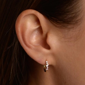 Close-up of gold S925 sterling silver hoop earrings with white zircon accents on ear