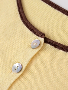 Détail de l'encolure ronde sur haut en tricot jaune avec bordure brune et boutons