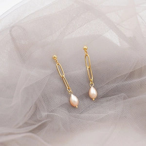 Elegant gold paperclip chain earrings with drop pearls on soft grey tulle background