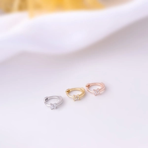 Detail of three geometric huggie hoop earrings in gold, silver and rose gold with zircons