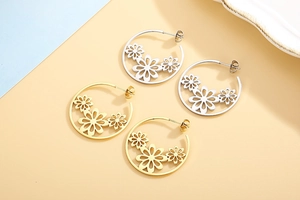 Detail of gold and silver stainless steel hoop earrings with hollow flower patterns