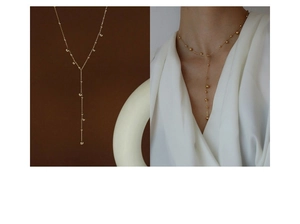 Detail of 18k gold plated Y-shaped necklace with metal beads and minimalist long pendant