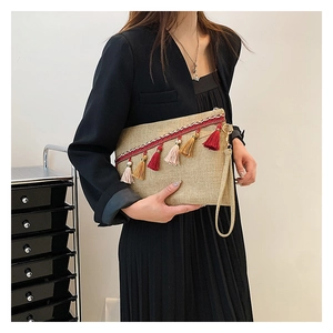 Detail of bohemian woven envelope clutch with colorful tassels and hand strap
