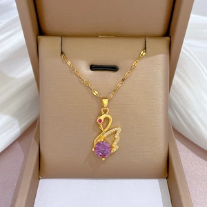 Close-up of golden swan necklace with pink crystal and pavé diamonds in a jewelry box