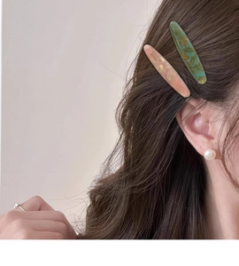 Détail de barrettes en acétate faites main rose et vert sur les cheveux
