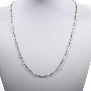 Detail view of a gold-plated beaded chain necklace with turquoise enamel beads on a bust