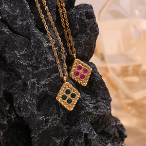 Macro detail of geometric rhombus pendant in 18K gold finish with pink and green stones