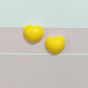Close-up of bright yellow macaron heart resin charms for DIY hair clips and phone cases