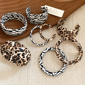 Detailed view of leopard and zebra print leather cuff bracelets on textured background