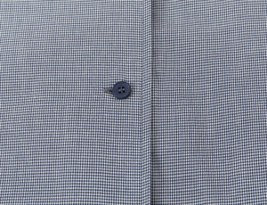 Vue macro du tissu en popeline à carreaux bleus et blancs avec bouton rond bleu foncé