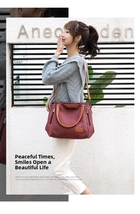 Detail of burgundy canvas tote bag with brown leather straps and side zipper pocket