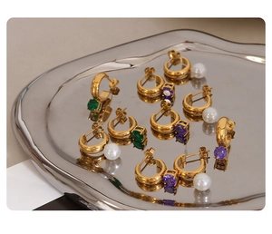 Macro view of gold-plated hoop earrings with emerald, purple zircon, and white pearls