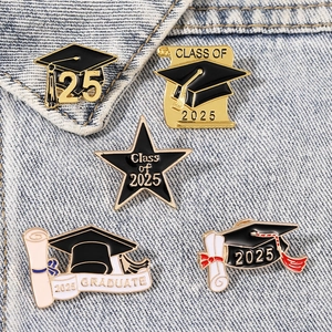 Close-up of five 2025 graduation enamel pins styled on a blue denim jacket collar