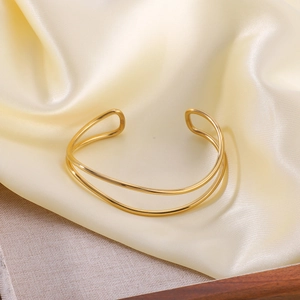 Minimalistisches goldfarbenes Doppel-Linien-Armband auf beigem Seidenhintergrund