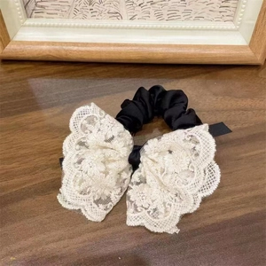 Detail of black satin and cream floral lace scrunchie with embroidery on wood