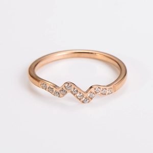 Macro detail of rose gold wavy ring featuring sparkling white cubic zirconia stones